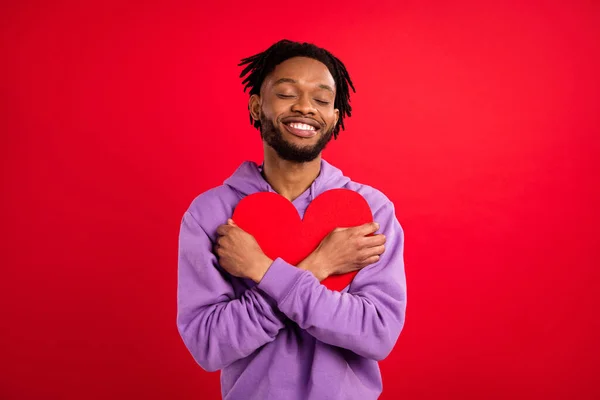 Foto retrato homem sorrindo abraçando coração vermelho cartão postal isolado vibrante cor vermelha fundo — Fotografia de Stock