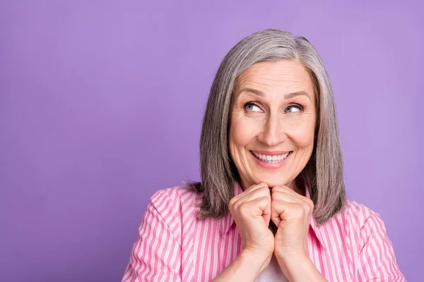 Foto van volwassen vrouw gelukkig positieve glimlach handen aanraken kin droom blik leeg ruimte geïsoleerd over violette kleur achtergrond — Stockfoto