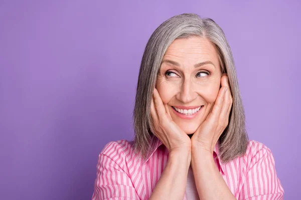 Foto da mulher idosa feliz sorriso positivo mãos toque bochechas sonho olhar espaço vazio isolado sobre cor roxa fundo — Fotografia de Stock