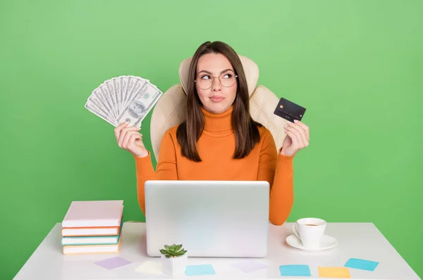 Portret van aantrekkelijke trendy minded meisje werken op afstand houden cash bank kaart kopen pay order geïsoleerd over fel groene kleur achtergrond — Stockfoto