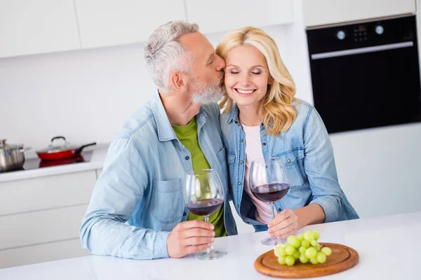 Foto de adorable lindo sonriente pareja casada cónyuges celebrar aniversario fecha bebida vino marido beso esposa cariñoso — Foto de Stock