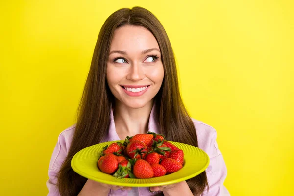 Φωτογραφία πορτρέτο νεαρή γυναίκα κρατώντας πιάτο με φράουλες χαμογελώντας αναζητούν copyspace απομονωμένο ζωντανό κίτρινο χρώμα φόντο — Φωτογραφία Αρχείου
