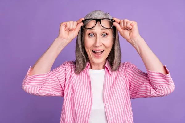 Фото взволнованной пожилой женщины счастливой позитивной улыбкой удивлены потрясенные руки касаются очки изолированы на фиолетовом фоне цвета — стоковое фото