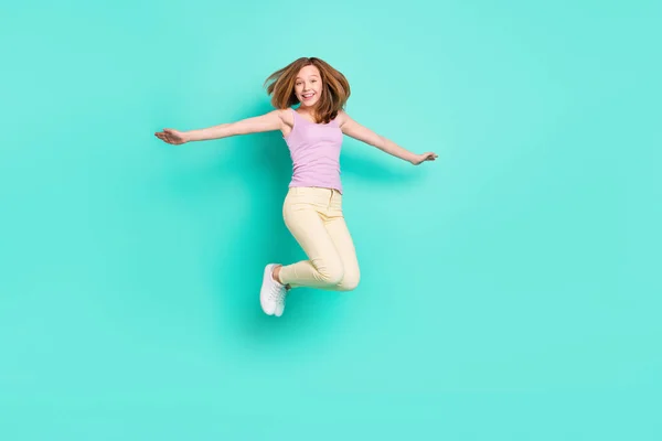 Volledige lengte foto van mooie bruine tiener meisje springen dragen top broek geïsoleerd op teal kleur achtergrond — Stockfoto