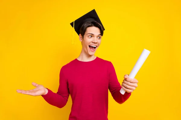 Photo de drôle brunet millennial guy hold papier porter chapeau pull rouge isolé sur fond de couleur jaune — Photo