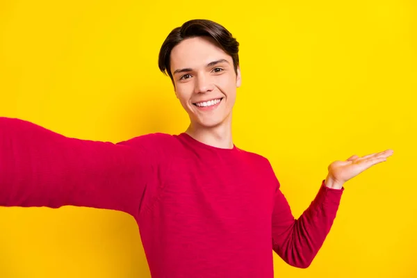 Foto von lustigen süßen jungen Herrn tragen roten Pullover mit Arm leeren Raum lächelnd isoliert gelbe Farbe Hintergrund — Stockfoto