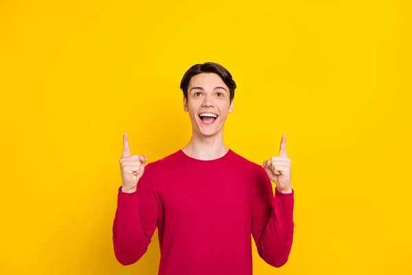 Foto de atraente impressionado jovem pescoço vestido pulôver vermelho sorrindo apontando dedos para cima espaço vazio isolado cor amarela fundo — Fotografia de Stock