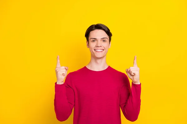 Foto van zoete aantrekkelijke jonge man gekleed rode trui glimlachen wijzende vingers omhoog lege ruimte geïsoleerde gele kleur achtergrond — Stockfoto