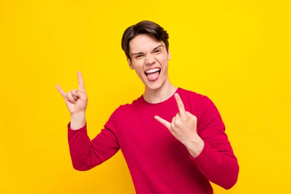 Foto von funky gehörnten jungen Mann gekleidet roten Pullover lächelnd zeigt Hard Rock Zeichen isoliert gelbe Farbe Hintergrund — Stockfoto
