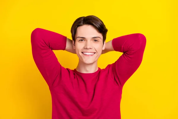 Zdjęcie pozytywne atrakcyjny młody facet szyi ubrany czerwony pullover uśmiechnięte ramiona za głową odizolowany żółty kolor tło — Zdjęcie stockowe