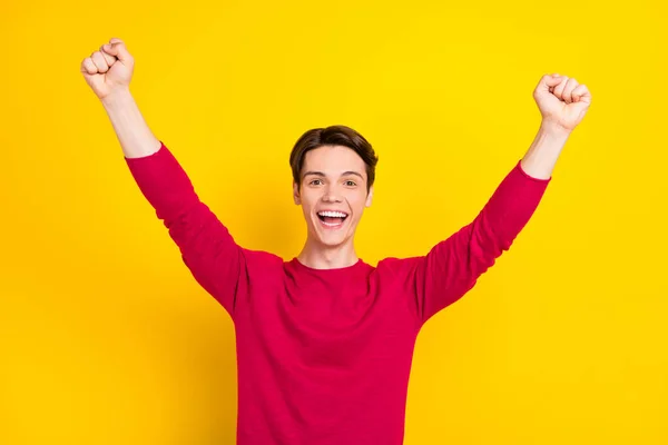 Photo de charmant jeune homme chanceux porter pull rouge levant poings sourire isolé fond de couleur jaune — Photo