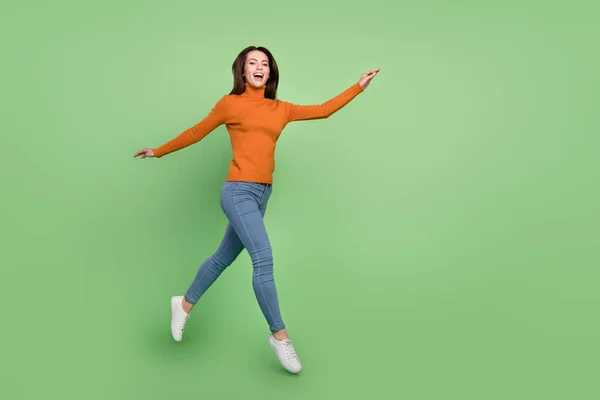 フル長いですボディサイズビューのかなり陽気な女の子ジャンプ歩く良い気分絶縁上の明るい緑の背景 — ストック写真