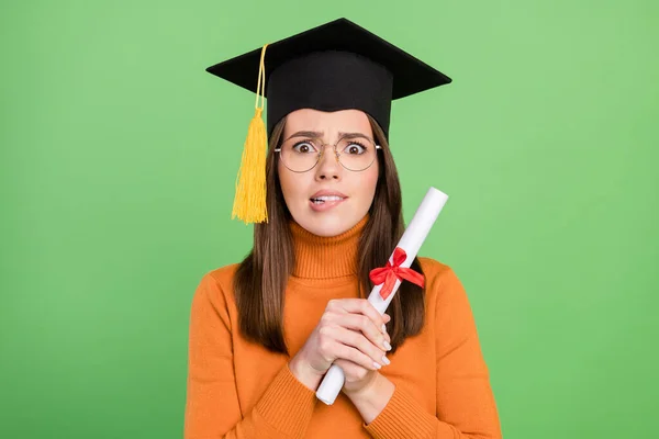 Portrait of attractive worried girl holding scroll paper letter license degree biting lip isolated over green color background — Stock Photo, Image