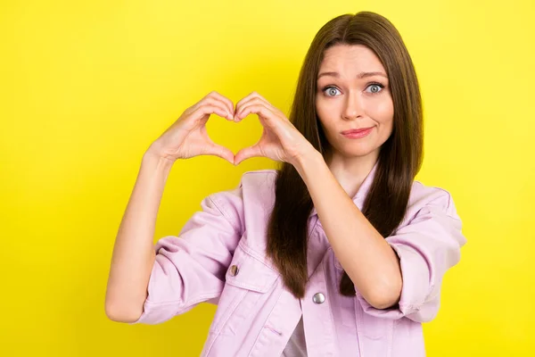 Portrett av tiltalende forvirret tvilende jente som viser hjertesymbol isolert over lys gul fargebakgrunn – stockfoto
