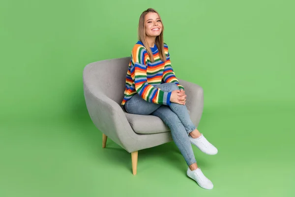 Volledige lengte body size foto lachend meisje zitten in grijze stoel dragen casual kleding geïsoleerde pastel groene kleur achtergrond — Stockfoto