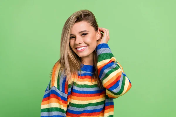 Foto retrato chica tocando el pelo sonriente usando suéter rayado aislado pastel color verde fondo —  Fotos de Stock