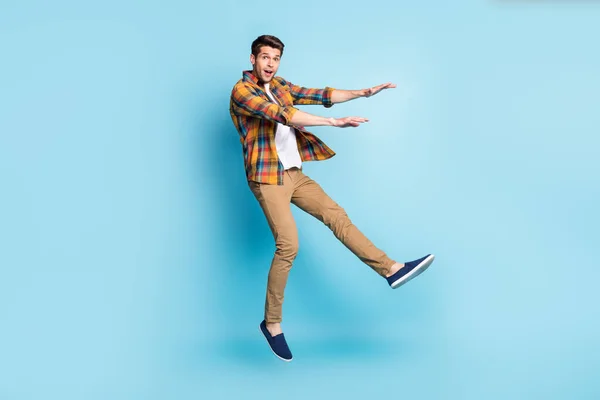 Photo of friendly cute young guy dressed plaid shirt smiling jumping high isolated blue color background — Stock Photo, Image