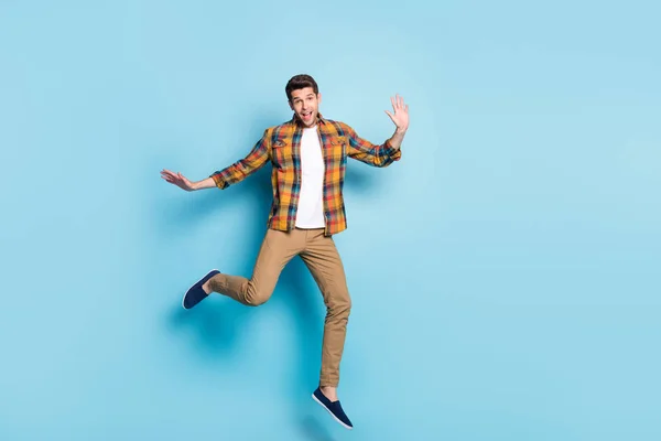 Foto von aufgeregten lustigen jungen Mann gekleidet kariertes Hemd Brille lächelnd springen hohe isolierte blaue Farbe Hintergrund — Stockfoto