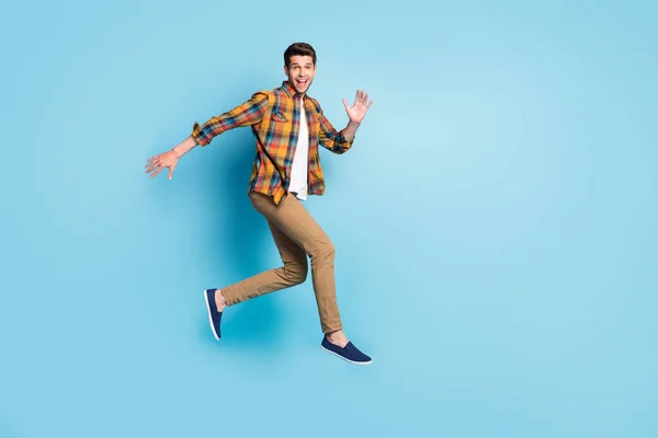 Photo of sweet excited young guy dressed plaid shirt spectacles smiling jumping high isolated blue color background — Stock Photo, Image