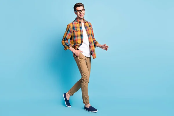 Фото фанки довольно молодой джентльмен носить клетчатые рубашки очки ходьба улыбаясь изолированный синий цвет фона — стоковое фото