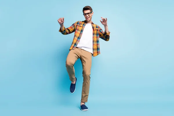 Foto van zelfverzekerde funky jonge man gekleed geruite shirt glimlachen dansen geïsoleerde blauwe kleur achtergrond — Stockfoto