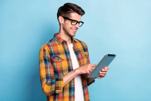 Retrato de atractivo alegre chico enfocado experto friki utilizando dispositivo de navegación web aislado sobre fondo de color azul brillante — Foto de Stock