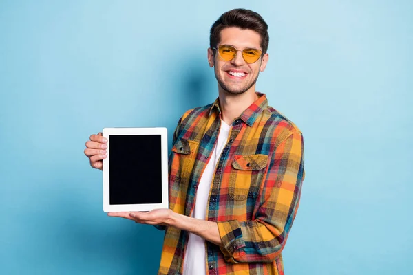 Портрет привлекательного веселого парня, держащего в руках устройство электронной книги пространство для копирования изолированы на ярко-голубом фоне цвета — стоковое фото