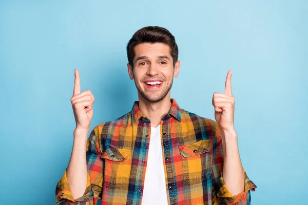 Retrato de chico alegre atractivo apuntando los dedos delanteros hacia arriba copia espacio vacío aislado sobre fondo de color azul brillante —  Fotos de Stock