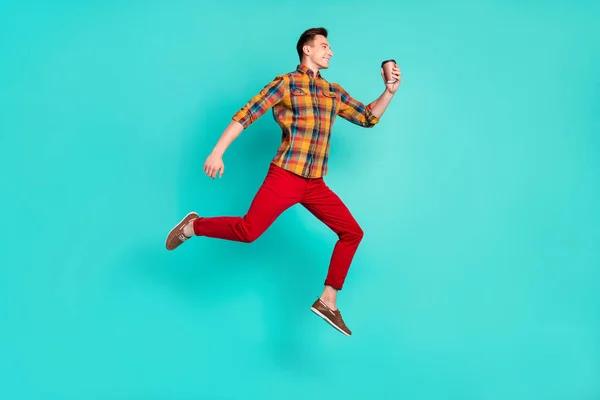 Pleine longueur profil photo de drôle brunet millennial guy saut tenir café porter chemise turquoise baskets isolé sur fond de sarcelle — Photo