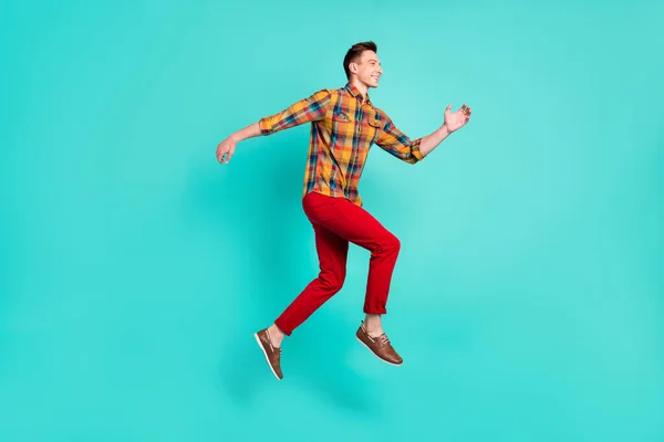 Foto de perfil em tamanho completo de funky brunet jovem cara salto desgaste camisa tênis turquesa isolado no fundo teal — Fotografia de Stock