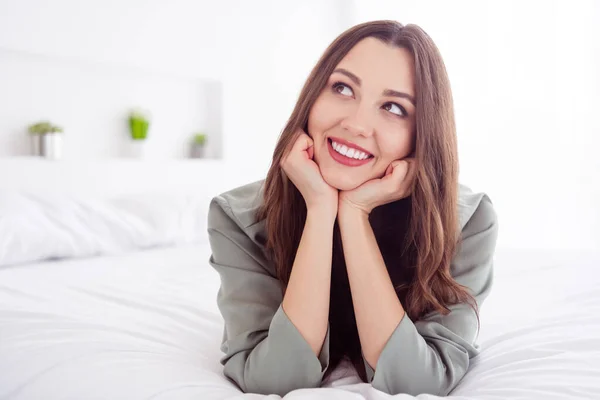 Foto de encantadora mulher sonhadora camisola cinza deitado braços de cama bochechas sorrindo dentro de casa interior quarto — Fotografia de Stock