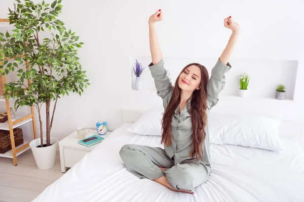 Portrait of attractive dreamy cheerful girl sitting on bed stretching waking up at home house light white interior — Stock Photo, Image