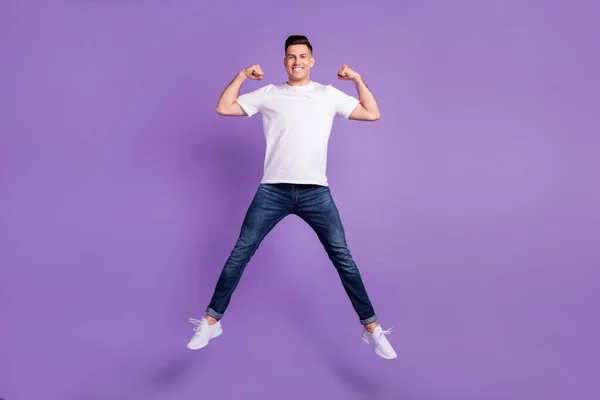 In voller Länge Foto des jungen Mannes glücklich positives Lächeln springen bis zeigen Muskeln sportlich isoliert über violette Farbe Hintergrund — Stockfoto