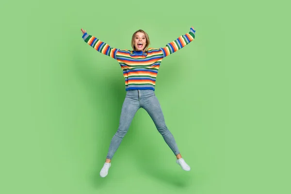 Longitud completa tamaño del cuerpo foto chica en suéter a rayas saltando alegre riendo aislado pastel color verde fondo —  Fotos de Stock