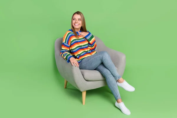 Full length body size photo smiling girl sitting in chair casual clothes looking empty space isolated pastel green color background — Stock Photo, Image