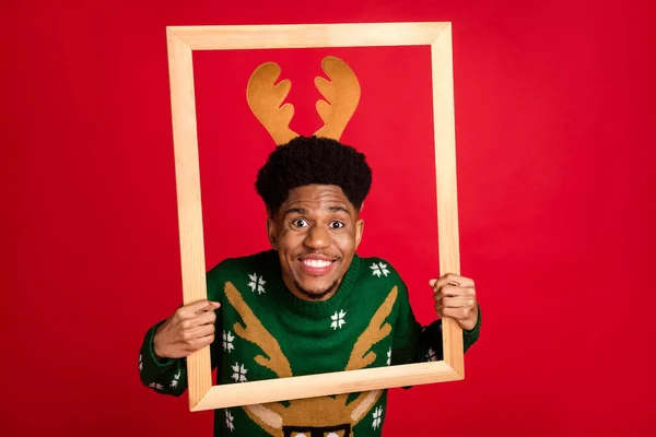 Retrato de chico alegre atractivo sosteniendo marco de fotos de madera teniendo recuerdos de invierno divertidos aislados sobre fondo de color rojo brillante — Foto de Stock