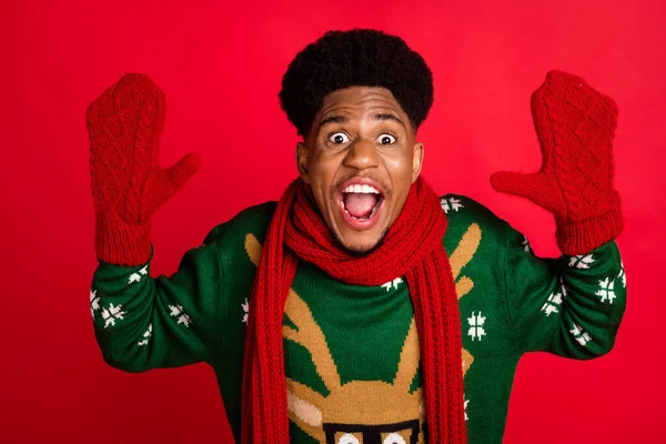 Foto von fröhlichen verrückten Kerl schreien erhöhen Palmen tragen Weihnachtspullover gestrickten Schal Handschuhe isoliert auf rotem Hintergrund — Stockfoto