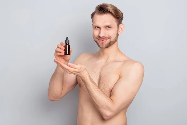 Photo of confident sweet blond hair young guy no clothes smiling holding arms oil bottle isolated grey color background — Stock Photo, Image