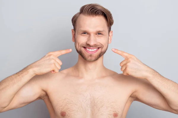 Foto van mooie blonde hairdo man punt tanden zonder kleren geïsoleerd op grijze achtergrond — Stockfoto