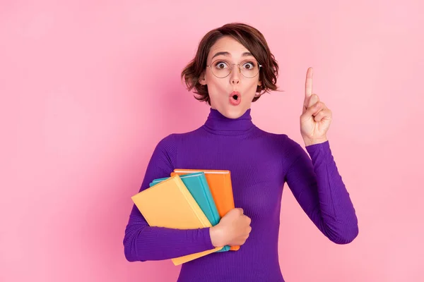 Fotografie chytré brunetky mladá dáma držet knihy bod nahoru nosit brýle fialový svetr izolované na růžovém pozadí — Stock fotografie