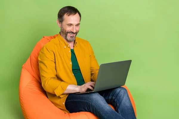 Profile side photo of mature business man happy positive smile chat laptop seat chair bean isolated over green color background — Stock Photo, Image