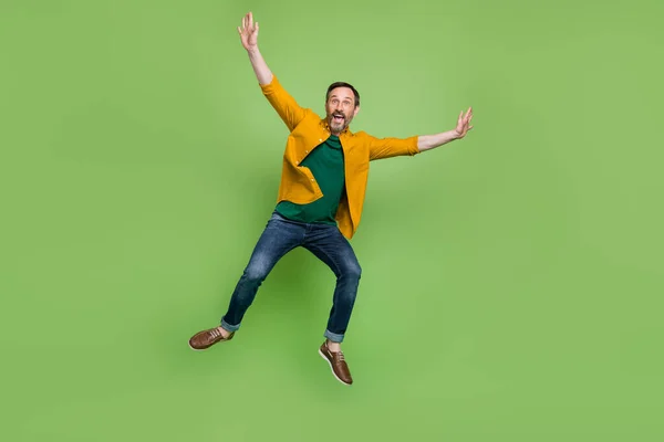 Full body photo of positive mature happy man jump up air raise hands enjoy isolated on green color background — Stock Photo, Image