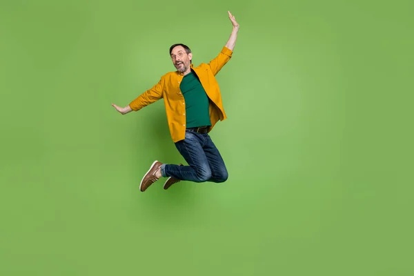 Largura completa foto de feliz alegre hombre maduro saltar disfrutar de fin de semana sonrisa aislado en el fondo de color verde —  Fotos de Stock