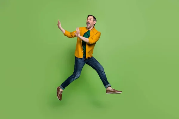 Full längd foto av upphetsad mogen man glad positiv leende hoppa upp ser tomt utrymme isolerad över grön färg bakgrund — Stockfoto