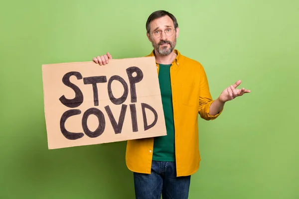 Foto de hombre maduro protesta mantenga pancarta parada coronavirus bloqueo restricción aislado sobre fondo de color verde — Foto de Stock