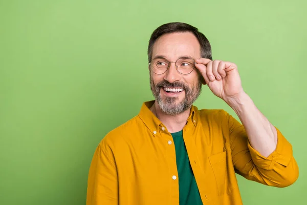 Foto de hombre maduro feliz sonrisa positiva mirada curiosa espacio vacío mano tacto gafas aisladas sobre fondo de color verde —  Fotos de Stock