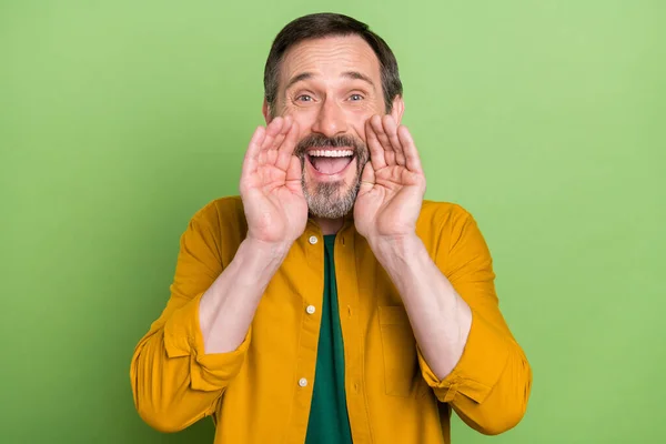 Photo de gai positif mature homme tenir les mains visage bouche dire des informations isolées sur fond de couleur verte — Photo