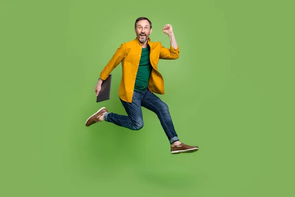 Full size profile side photo of mature business man happy positive smile jump up hold laptop isolated over green color background — Stockfoto