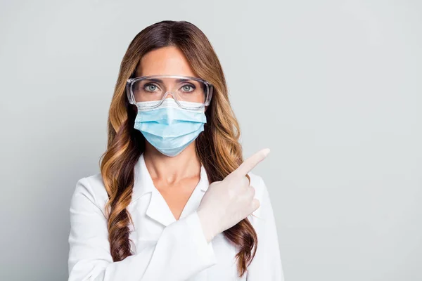 Porträt der attraktiven welligen Frau doc trägt Maske zeigt Kopierraum isoliert über grauen Pastellfarben Hintergrund — Stockfoto