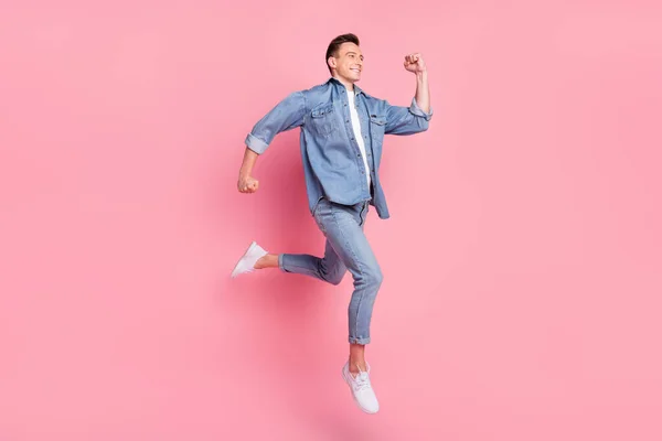Foto lateral de perfil de tamaño completo del joven chico sonriente de buen humor corriendo en el aire velocidad rápida aislado en el fondo de color rosa —  Fotos de Stock